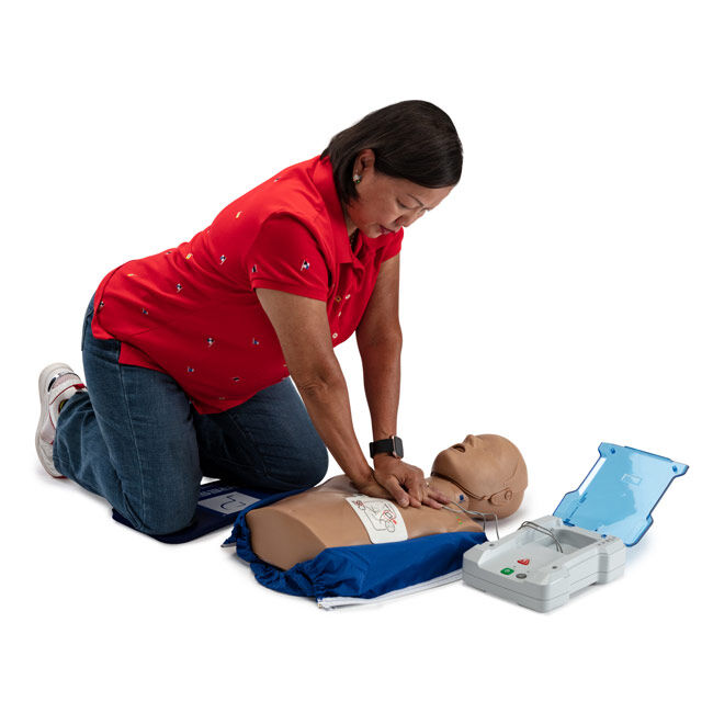 Student practicing CPR compressions and using a Prestan Professional AED Trainer PLUS on a CPR manikin.