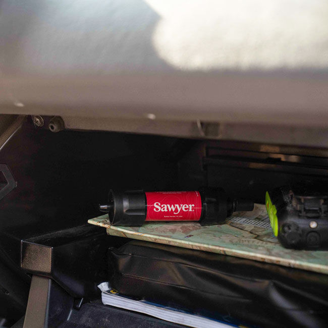 Sawyer Mini Water Filter installed in glove box as part of an outdoor emergency water filtration setup.