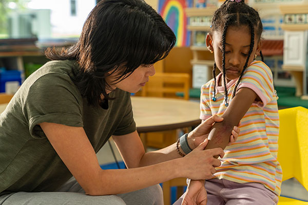 A Norfolk, Virginia teacher inspects a scrape on a student's arm.