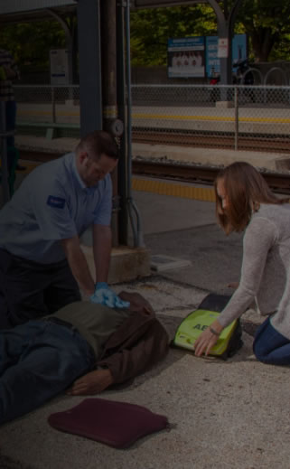 Image of two individuals using an AED and performing CPR on an incapacitated individual.