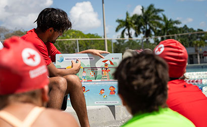 A Red Cross Swimming Instructor showing students an infographic of water safety tips.