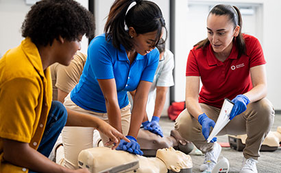 Red Cross Instructor teaching students techniques for CPR compressions with CPR manikins.
