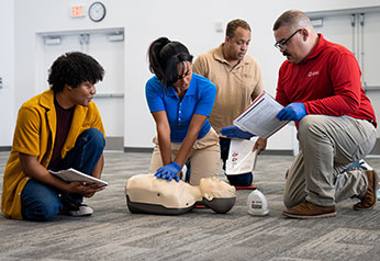 Red Cross Instructor teaching individuals high quality CPR in a classroom.
