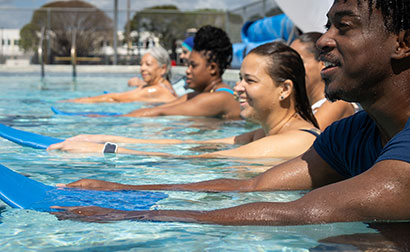 A group of people holding kickboards during swimming lessons.